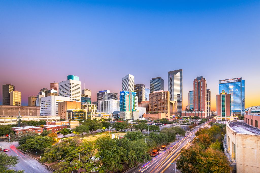 Downtown Houston, Texas skyline and city streets with traffic light streaks at twilight, representing reliable corporate transportation, executive car, and limousine services.
